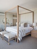 Four-poster bed against patterned wallpaper and antique chest of drawers in country-house-style bedroom