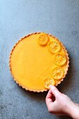 Female hand decorating a lemon tart with lemon slices