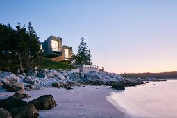 Zwei moderne Strandhäuser in Küstenlandschaft und romantischer Abendstimmung