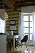 Chair and white dining table in front of retro wallpaper and French window in renovated period apartment