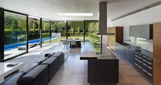 Designer-style open-plan interior with view of garden and pool through glass façade