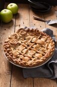 Apple pie with a dough lattice and pastry roses in a tin