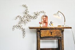 Artistic floral paper decoration on wall next to antique wooden table and retro lamp