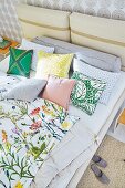 A double bed with floral bed linen and cushions
