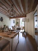 Chandelier and rustic wood-beamed ceiling in dining area with historical ambiance