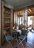 Bread on bistro table and two folding chairs in front of cupboard and view of chandelier in living area