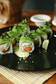 Sushi rolls with salmon, avocado, fresh cheese and green coloured fish roe