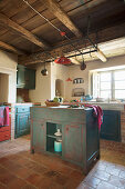 Island counter in Mediterranean kitchen with distressed blue and red cabinets