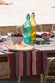 Colourful bottles and striped tablecloth on set table