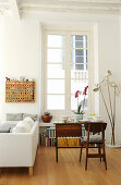 Orchids on set table, standard lamp and sofa in front of lattice window in period apartment