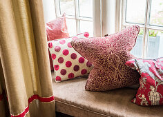 Cushions with various red-patterned covers on windowseat