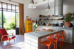 Concrete table and colourful plastic chairs in industrial-style kitchen