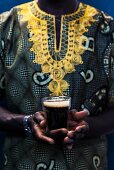Senegalese in traditionellem Boubou hält ein Glas Touba (Kaffeegetränk, Senegal, Afrika)