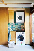 Waschküche hinter einer Schiebetür mit hängender Waschmaschine