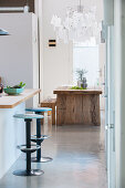 Bar stools at kitchen counter with rustic dining table in background