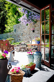 Flowers on windowsill with view of terrace with stone back wall