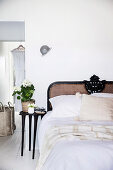 Bedside table with hydrangea next to bed and passage to walk-in wardrobe