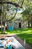 Set breakfast table on wooden terrace with hammock in background