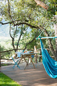 Blue hammock and set breakfast table on wooden terrace