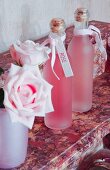 Flaschen mit Etikett neben Rosen auf roséfarbenem Marmor