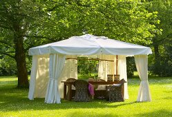 Wicker furniture in elegant white pavilion on summer lawn