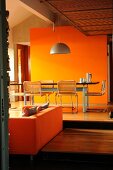 Esstisch vor orangefarbener Wand auf einer höheren Ebene