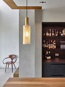 Drinks cabinet in open-plan kitchen, pendant lamp above dining table and designer chair in background