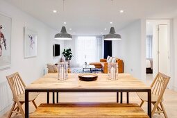 Esstisch mit Metallgestell und Holzplatte, Holzbank und Holzstühle in offenem Wohnraum