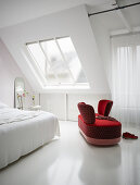 Rotes Sofa mit gegenüberstehenden Lehnen im weißen Schlafzimmer