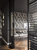 View into office with patterned wallpaper and glass wall with louvre blinds