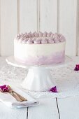A cream cake with lilac piping