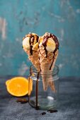 Orange ice cream with chocolate sauce and chopped hazelnuts