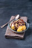 Orange ice cream with chocolate sauce and chopped hazelnuts in a bowl