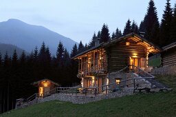Log cabin with illuminated windows in mountains