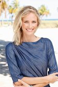 A blonde woman wearing a denim dress on the beach