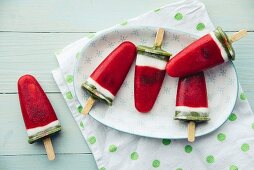Popsicles made of strawberry with chocolate chips, coconut cream and kiwi
