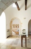 Foyer with arched doorways and glass-topped table with wooden base in foyer of trullo