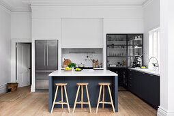 Three bar stools on the kitchen island in a large old-style kitchen