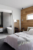 Double bed in bedroom with wall made from recycled oak, view of bathroom ensuite