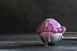 A scoop of blueberry ice cream in an ice cream scoop