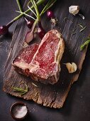 A raw, dry-aged T-bone steak on a wooden board