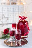 Selbstgemachter Brombeerlikör in Flasche und Gläsern für Weihnachten