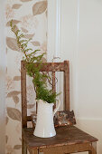 Branches in jug on old wooden chair