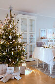 Verpackte Geschenke unterm Weihnachtsbaum neben dem gedeckten Tisch