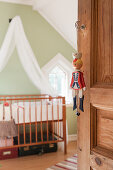 Puppet hung from hand of wooden door leading into vintage-style nursery