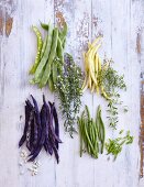 Colourful beans and herbs on a white wooden background