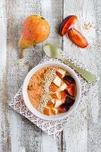 A smoothie bowl with buckwheat groats, plum, orange, pear and sesame seeds