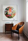 Classic armchair next to retro lamp on antique cabinet below modern colourful painting