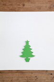 Christmas-tree silhouette cut out of green paper on white surface