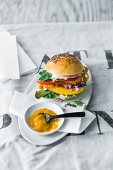 A crispy chicken burger with mango slices and mango ketchup